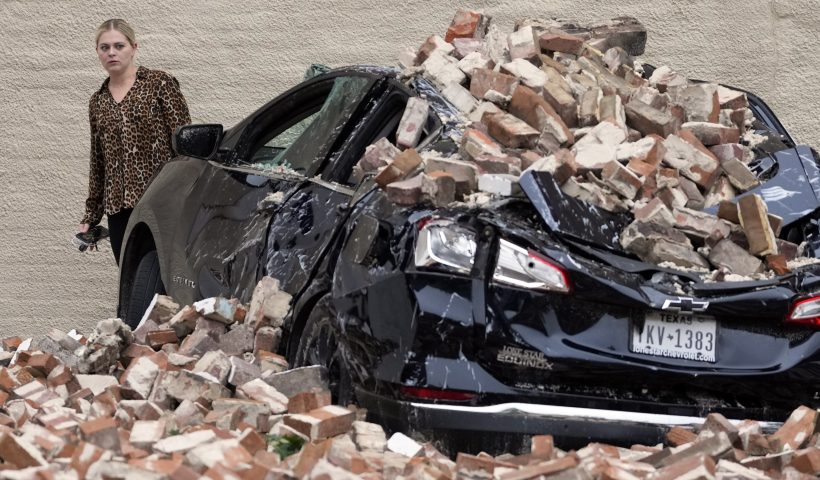 A woman looks at the damage caused by fallen bricks from a building wall in the aftermath of a severe thunderstorm Friday, May 17, 2024, in Houston. Thunderstorms pummeled southeastern Texas on Thursday, killing at least four people, blowing out windows in high-rise buildings and knocking out power to more than 900,000 homes and businesses in the Houston area. (AP Photo/David J. Phillip)