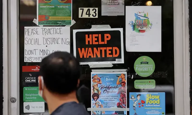 A pedestrian passes a "Help Wanted" sign in the door of a hardware store in Cambridge, Massachusetts, U.S., July 8, 2022. REUTERS/Brian Snyder/File Photo