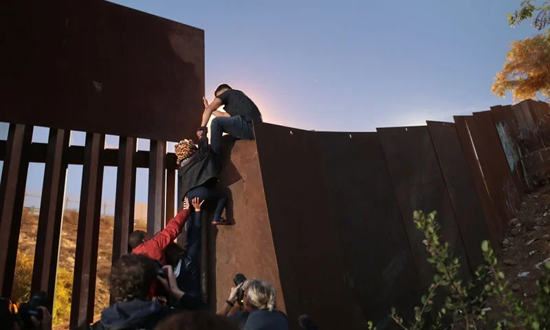 TIJUANA, MEXICO - DECEMBER 03: Members of the migrant caravan climb over the U.S.-Mexico border fence on December 3, 2018 while crossing into San Diego, CA from Tijuana, Mexico. Many had planned to request political asylum in the United States after traveling more than 6 weeks from Central America. (Photo by John Moore/Getty Images)