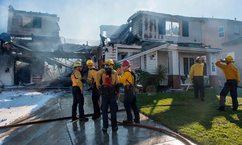 Firefighters hose down a burning house during the Tick Fire in Agua Dulce near Santa Clarita, California on October 25, 2019. - California firefighters battled through the night to contain a fast-moving wildfire driven by high winds that was threatening to engulf thousands of buildings. Around 40,000 people were told to flee the Tick Fire, which was raging across 4,000 acres (1,600 hectares) just north of Los Angeles. (Photo by Mark RALSTON / AFP) (Photo by MARK RALSTON/AFP via Getty Images)
