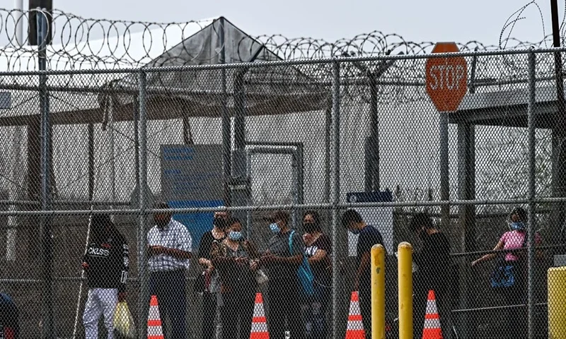 TOPSHOT - Migrants mostly form Central America wait in line to cross the border into the US at the Gateway International Bridge, between the cities of Brownsville, Texas, and Matamoros, Mexico, on March 15, 2021, in Brownsville, Texas. - It's the new normal for migrant families under President Joe Biden, after the harsh "zero tolerance" approach of Donald Trump dashed the dreams of hundreds of thousands hoping to escape endemic poverty and violence in Central America. Biden's pledge of a more humane approach though has sparked a new rush to the border, threatening to become a huge political liability. Republicans are accusing him of opening the country's doors to illegal border-crossers and sparking a "crisis" on the US-Mexico frontier, marked in Texas by the meandering Rio Grande river. (Photo by CHANDAN KHANNA / AFP) (Photo by CHANDAN KHANNA/AFP via Getty Images)