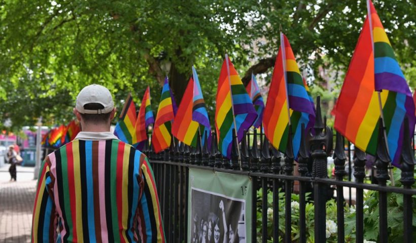 A person wearing a sweater with 'Progress Pride Flag' colors, including rainbow and black and brown stripes for communities of color, walks past rainbow flags at the Stonewall National Monument, the first US national monument dedicated to LGBTQ history and rights, marking the birthplace of the modern lesbian, gay, bisexual, transgender, and queer civil rights movement, on June 1, 2020 in New York City. (Photo by Angela Weiss / AFP) (Photo by ANGELA WEISS/AFP via Getty Images)
