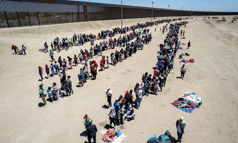 EL PASO, TEXAS - MAY 11: In an aerial view, immigrants line up to be processed to make asylum claims at a makeshift migrant camp on May 11, 2023 in El Paso, Texas. The number of immigrants reaching the border has surged with the end of the U.S. government's Covid-era Title 42 policy, which for the past three years has allowed for the quick expulsion of irregular migrants entering the country. (Photo by John Moore/Getty Images)