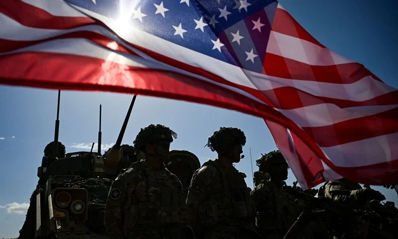 US Army soldiers stand in formation next to a US flag and a US Army armoured vehicle as they take part in the NATO "Noble Blueprint 23" joint military exercise at the Novo Selo military ground, northwestern Bulgaria, on September 26, 2023. More than two hundred soldiers from Bulgaria, Italy, USA, Greece, North Macedonia, Albania, Montenegro and Turkey are taking part in the exercise to demonstrate operational capabilities during the NATO "Noble Blueprint 23" joint exercise. (Photo by Nikolay DOYCHINOV / AFP) (Photo by NIKOLAY DOYCHINOV/AFP via Getty Images)