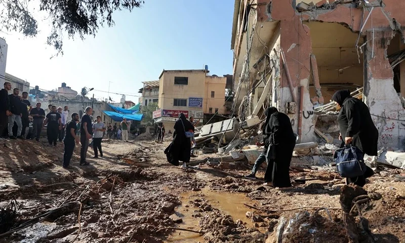 Palestinians walk next to a building damaged during a raid by Israeli troops at the Nur Shams refugee camp near the northern city of Tulkarm in the occupied West Bank on October 20, 2023. At least 81 Palestinians have been killed by Israeli troops or settlers in the West Bank since the Gaza conflict erupted on October 7, according to ministry figures. (Photo by Zain JAAFAR / AFP) (Photo by ZAIN JAAFAR/AFP via Getty Images)
