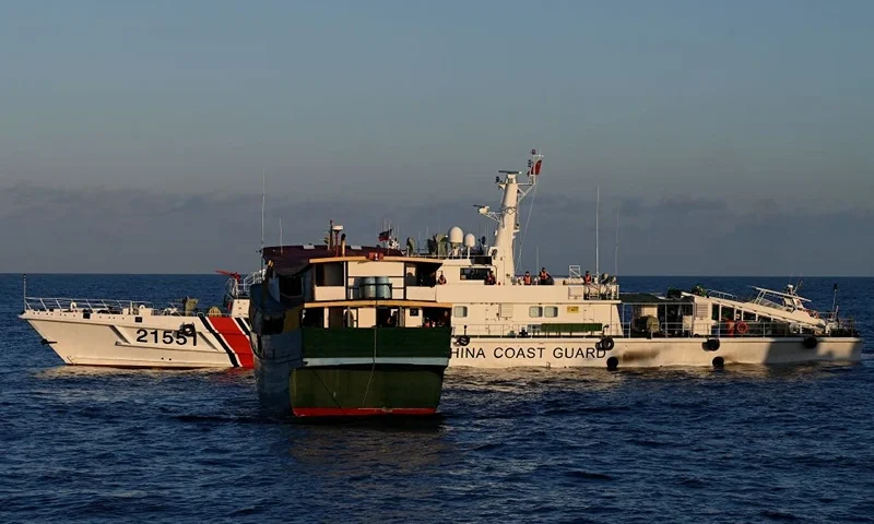 This photo taken on March 5, 2024 shows a China Coast Guard vessel (back) sailing near the Philippine military chartered Unaizah May 4 (front) during its supply mission to Second Thomas Shoal in the disputed South China Sea. The Philippines said on March 5 that China Coast Guard vessels caused two collisions with Philippine boats and water cannoned one of them, leaving four crew injured during a resupply mission in the South China Sea. (Photo by JAM STA ROSA / AFP) (Photo by JAM STA ROSA/AFP via Getty Images)