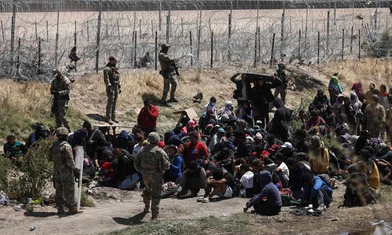 Migrants of different nationalities pray in front of anti-riot agents of the Texas National Guard who prevent passage towards their border line, as seen from Ciudad Juarez, state of Chihuahua, Mexico, on April 16, 2024. (Photo by Herika Martinez / AFP) (Photo by HERIKA MARTINEZ/AFP via Getty Images)