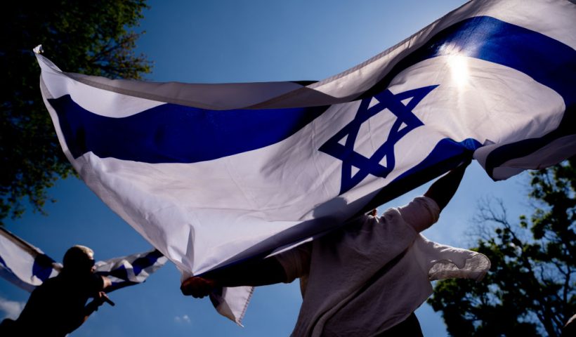WASHINGTON, DC - MAY 2: Michal Rokah of Falls Church, Virginia (C) and Israeli Matan Showstack of Washington, DC (L) dance and wave large Israeli flags during a rally against campus antisemitism at George Washington University on May 2, 2024 in Washington, DC. (Photo by Andrew Harnik/Getty Images)