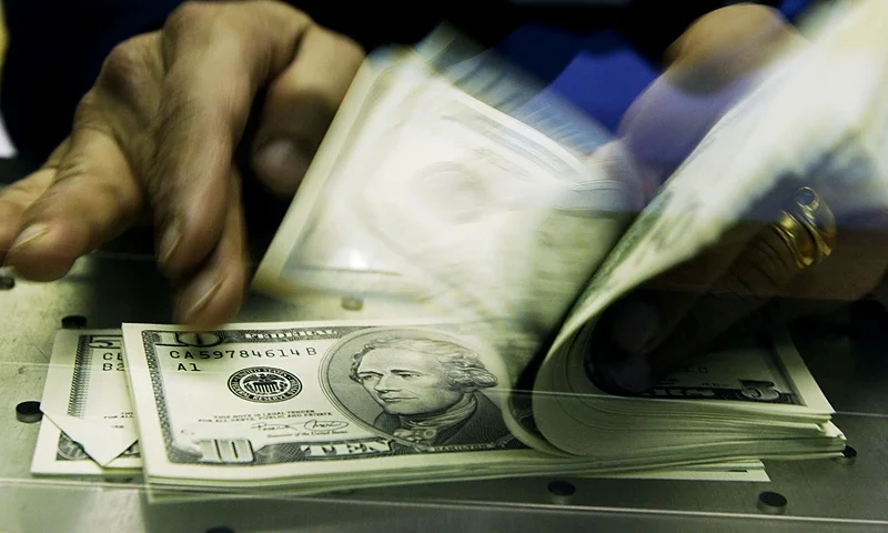 LONDON, ENGLAND - FEBRUARY 19: A cashier at a Travelex Bureau de Change counts U.S. Dollars in exchange for British pounds February 19, 2004 in London. The recent dramatic fall in the U.S.dollar has seen a rise in UK customers changing their pounds for the weaker greenback. (Photo by Ian Waldie/Getty Images) *** Local Caption ***