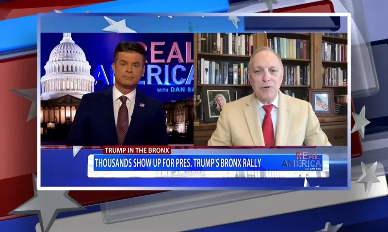 Video still from Real America on One America News Network showing a split screen of the host on the left side, and on the right side is the guest, Rep. Andy Biggs.