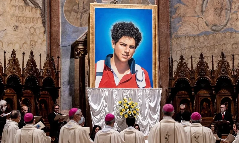 Beatification Of Carlo Acutis ASSISI, ITALY - OCTOBER 10: A tapestry featuring a portrait of Carlo Acutis is hang at the St. Francis Basilica during the beatification ceremony of Carlo Acutis, on October 10, 2020 in Assisi, Italy. The fifteen-year-old Carlo Acutis member of the Millennial generation who died on 12 October 2006 from M3 fulminant leukemia, is considered a "computer geek" on account of his passion and skill with computers and the internet. Acutis applied himself to creating a website dedicated to cataloguing each reported Eucharistic miracle in the world. (Photo by Vatican Pool/Getty Images)