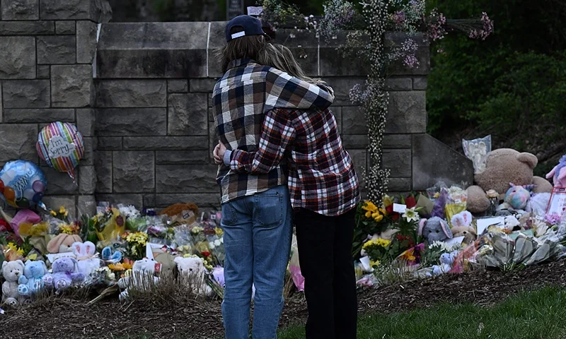 TOPSHOT - A couple pay their respects at a makeshift memorial for victims at the Covenant School building at the Covenant Presbyterian Church following a shooting, in Nashville, Tennessee, on March 28, 2023. - A heavily armed former student killed three young children and three staff in what appeared to be a carefully planned attack at a private elementary school in Nashville on March 27, before being shot dead by police. Chief of Police John Drake named the suspect as Audrey Hale, 28, who the officer later said identified as transgender. (Photo by Brendan SMIALOWSKI / AFP) (Photo by BRENDAN SMIALOWSKI/AFP via Getty Images)