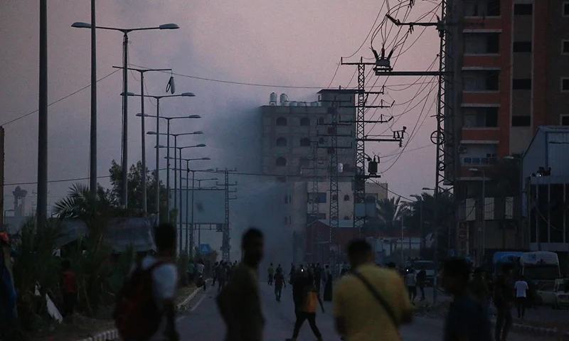 Palestinians watch smoke billowing following an Israeli airstrike in Deir al-Balah in the central Gaza Strip on June 6, 2024, amid the ongoing conflict between Israel and the Palestinian militant group Hamas. (Photo by Bashar TALEB / AFP) (Photo by BASHAR TALEB/AFP via Getty Images)