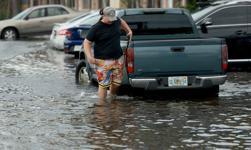 HALLANDALE BEACH, FLORIDA - JUNE 13: A person walks through a flooded street on June 13, 2024, in Hallandale Beach, Florida. Tropical moisture passing through the area has caused flooding due to the heavy rain. Forecasts are calling for more rain in an area already saturated with water. (Photo by Joe Raedle/Getty Images)