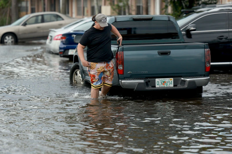 HALLANDALE BEACH, FLORIDA - JUNE 13: A person walks through a flooded street on June 13, 2024, in Hallandale Beach, Florida. Tropical moisture passing through the area has caused flooding due to the heavy rain. Forecasts are calling for more rain in an area already saturated with water. (Photo by Joe Raedle/Getty Images)