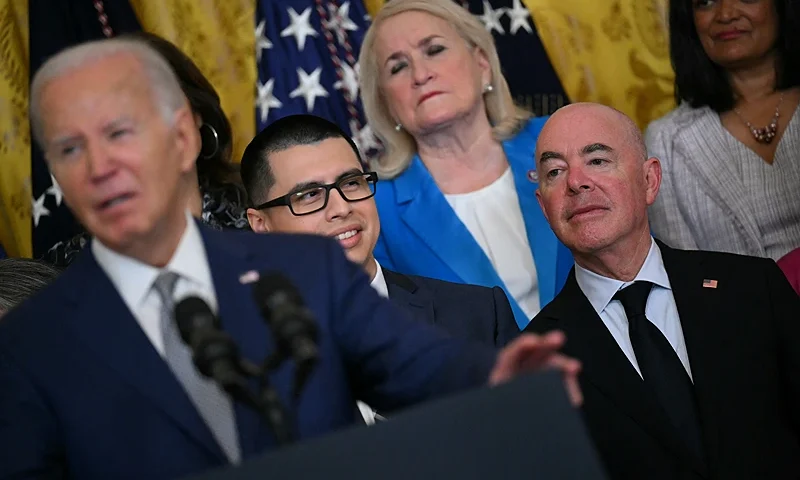 US Homeland Securty Secretary Alejandro Mayorkas (R) looks on as President Joe Biden speaks at an event marking the 12th anniversary of Deferred Action for Childhood Arrivals (DACA) at the White House in Washington, DC, on June 18, 2024. President Joe Biden announced Tuesday a new potential citizenship path for immigrants married to US nationals, balancing a recent crackdown on illegal border crossers in an attempt to thread a tricky pre-election political needle. (Photo by Drew ANGERER / AFP) (Photo by DREW ANGERER/AFP via Getty Images)