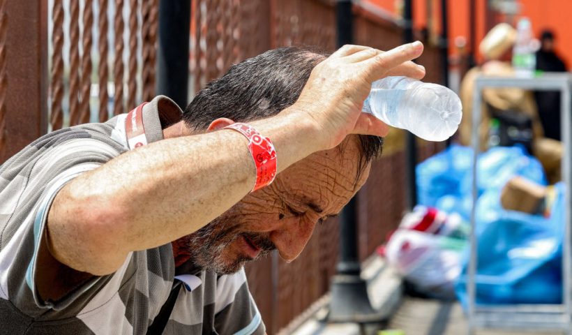 TOPSHOT - A departing Turkish Muslim pilgrim pours cold water from a bottle on his head to cool off as he waits in Saudi Arabia's holy city of Mecca on June 20, 2024. (Photo by Abdel Ghani BASHIR / AFP) (Photo by ABDEL GHANI BASHIR/AFP via Getty Images)
