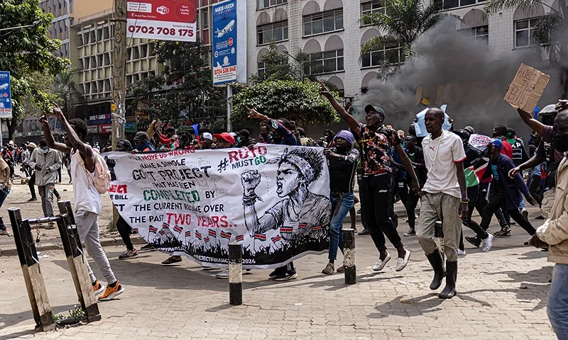 NAIROBI, KENYA - JUNE 25: Protesters march while carrying signs during a protest against the finance bill on June 25, 2024 in Nairobi, Kenya. Last week saw several days of protests, mainly by young Kenyans, against a proposed finance bill that promises to raise taxes on a variety of goods. The outcry spurred the government to withdraw several contentious provisions, including taxes on bread and vehicles, but the bill passed a second-round vote and a parliamentary committee is now considering amendments. (Photo by Patrick Meinhardt/Getty Images)