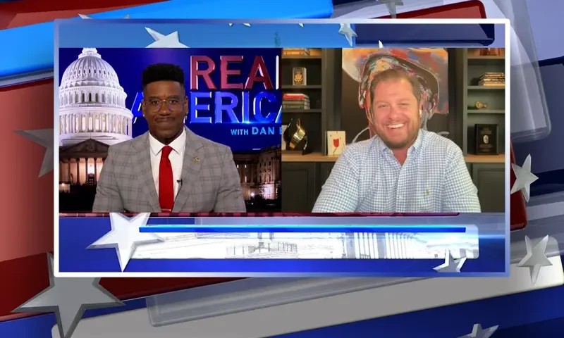 Video still from Real America on One America News Network showing a split screen of the host on the left side, and on the right side is the guest, Sen. Jake Hoffman.