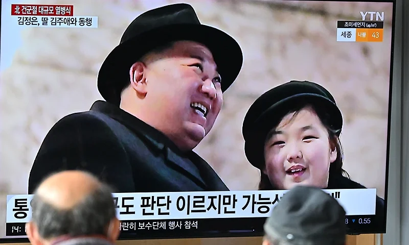 People watch a television screen showing a news broadcast with an image of North Korean leader Kim Jong Un (L) and his daughter presumed to be named Ju Ae (R) attending a military parade held in Pyongyang to mark the 75th founding anniversary of its armed forces, at a railway station in Seoul on February 9, 2023. North Korea's Kim Jong Un oversaw a major military parade showcasing a record number of nuclear and intercontinental ballistic missiles, state media reported on February 9, including what analysts said was possibly a new solid-fueled ICBM. (Photo by Jung Yeon-je / AFP) (Photo by JUNG YEON-JE/AFP via Getty Images)