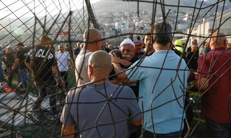 TOPSHOT - Local residents comfort each other as they gather at a site where a reported strike from Lebanon fell in Majdal Shams village in the Israeli-annexed Golan area on July 27, 2024. Israel's emergency medical service Magen David Adom said at least nine people were killed and 34 wounded including 17 in critical condition, after a rocket fired from Lebanon had hit the town of Majdal Shams in the Israeli-annexed Golan Heights. (Photo by Jalaa MAREY / AFP) (Photo by JALAA MAREY/AFP via Getty Images)