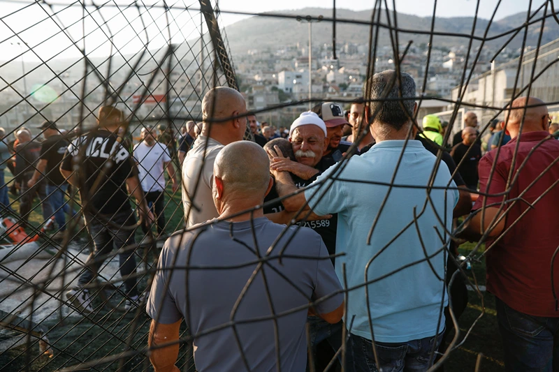 TOPSHOT - Local residents comfort each other as they gather at a site where a reported strike from Lebanon fell in Majdal Shams village in the Israeli-annexed Golan area on July 27, 2024. Israel's emergency medical service Magen David Adom said at least nine people were killed and 34 wounded including 17 in critical condition, after a rocket fired from Lebanon had hit the town of Majdal Shams in the Israeli-annexed Golan Heights. (Photo by Jalaa MAREY / AFP) (Photo by JALAA MAREY/AFP via Getty Images)