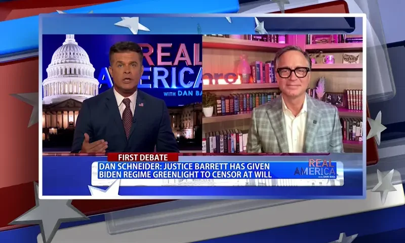 Video still from Real America on One America News Network showing a split screen of the host on the left side, and on the right side is the guest, Dan Schneider.