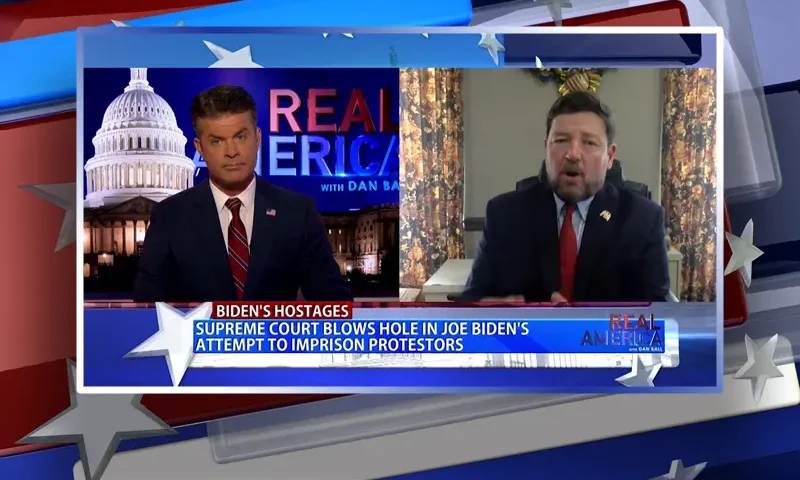 Video still from Real America on One America News Network showing a split screen of the host on the left side, and on the right side is the guest, Ed Martin.
