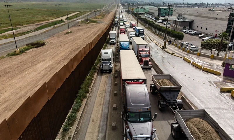 Aerial view of cargo trucks lining up to cross to the United States near the US-Mexico border at Otay Mesa crossing port in Tijuana, Baja California state, Mexico, on April 4, 2019. - US President Donald Trump is expected to visit a section of the border fence in Calexico during his tour to California on Friday. (Photo by Guillermo Arias / AFP) (Photo credit should read GUILLERMO ARIAS/AFP via Getty Images)