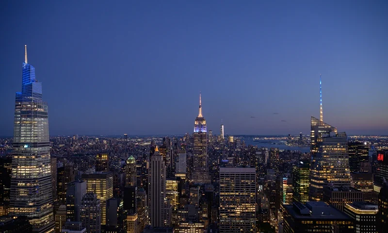 Landmark buildings of the Manhattan city skyline including the Empire State building (C) and One World Trade Center (C-R) are illuminated in blue and gold in celebration of reaching 70 percent of New York adults having received their first dose of the Covid-19 vaccine, in New York on June 15, 2021. (Photo by Ed JONES / AFP) (Photo by ED JONES/AFP via Getty Images)
