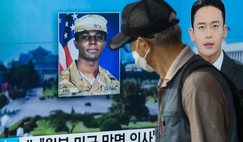In this photo taken in Seoul on August 16, 2023, a man walks past a television showing a news broadcast featuring a photo of US soldier Travis King (C), who ran across the border into North Korea while part of a tour group visiting the Demilitarized Zone on South Korea's border on July 18. Travis King defected to North Korea to escape "mistreatment and racial discrimination in the US Army", state media said Wednesday, Pyongyang's first official confirmation they were holding the American soldier. (Photo by Anthony WALLACE / AFP) (Photo by ANTHONY WALLACE/AFP via Getty Images)