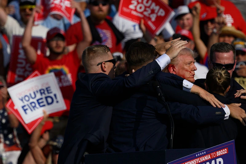 BUTLER, PENNSYLVANIA - JULY 13: Republican presidential candidate, former U.S. President Donald Trump is whisked away by Secret Service after shots rang out at a campaign rally at Butler Farm Show Inc. on July 13, 2024 in Butler, Pennsylvania. Trump slumped and injuries were visible to the side of his head. Butler County district attorney Richard Goldinger said the shooter and one audience member are dead and another was injured. (Photo by Jeff Swensen/Getty Images)