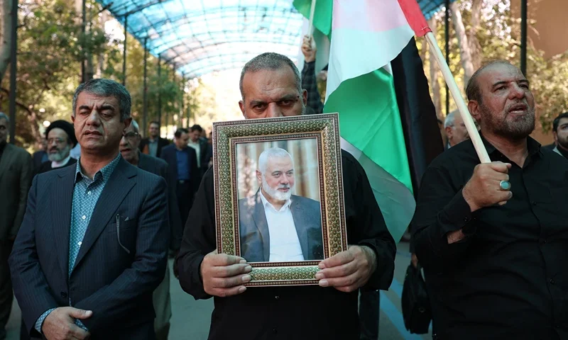 TOPSHOT - People hold up the Palestinian flag and a portrait of assassinated Hamas chief Ismail Haniyeh Hamas, during a rally at Tehran University, in the Iranian capital Tehran on July 31, 2024, as Iran declares three days of mourning. The Palestinian militant group Hamas said on July 31, its political leader Ismail Haniyeh was killed in an Israeli strike in Iran, where he was attending the inauguration of the country's new president, and vowed the act "will not go unanswered". (Photo by AFP) (Photo by -/AFP via Getty Images)
