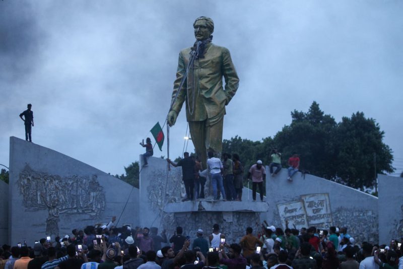 Anti-government protestors attempt to vandalise a statue of Sheikh Mujibur Rahman, Bangladesh's founding father and parent of the country's ousted Prime Minister Sheikh Hasina, in Dhaka on August 5, 2024. Bangladeshi Prime Minister Sheikh Hasina's 15-year rule ended on August 5, as she fled after more than a month of deadly protests as the military announced it would form an interim government. (Photo by Abu SUFIAN JEWEL / AFP) (Photo by ABU SUFIAN JEWEL/AFP via Getty Images)