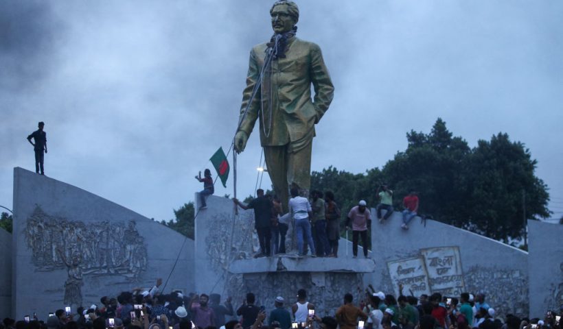 Anti-government protestors attempt to vandalise a statue of Sheikh Mujibur Rahman, Bangladesh's founding father and parent of the country's ousted Prime Minister Sheikh Hasina, in Dhaka on August 5, 2024. Bangladeshi Prime Minister Sheikh Hasina's 15-year rule ended on August 5, as she fled after more than a month of deadly protests as the military announced it would form an interim government. (Photo by Abu SUFIAN JEWEL / AFP) (Photo by ABU SUFIAN JEWEL/AFP via Getty Images)