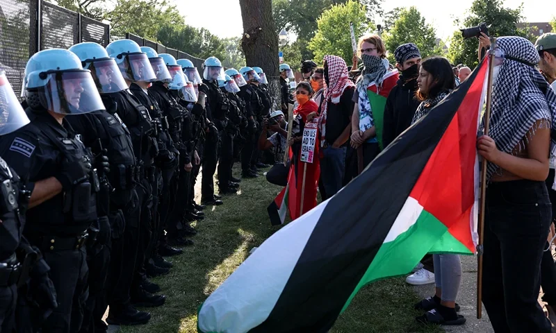 TOPSHOT - Pro-Palestinian activists face police during a demonstration outside the venue of the Democratic National Convention (DNC) in Chicago, Illinois, on August 19, 2024. ice President Kamala Harris will formally accept the party's nomination for president at the DNC which runs from August 19-22 in Chicago. (Photo by Alex WROBLEWSKI / AFP) (Photo by ALEX WROBLEWSKI/AFP via Getty Images)