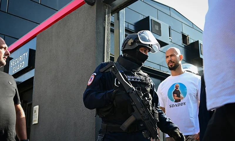 Andrew Tate (C), is brought in for questioning by the Romanian gendarmes after a ten-hour long raid by police at their residency in Bucharest on August 21, 2024. Romanian authorities on August 21, 2024 searched the home of controversial influencer Andrew Tate, who is awaiting trial over human trafficking and rape charges, as part of a new investigation, officials said. One of the world's best-known influencers known for misogynist and sometimes violent maxims, Andrew Tate has been accused of having formed an organised criminal network in early 2021 in Romania and Britain, along with his brother Tristan. They have denied the charges. (Photo by Daniel MIHAILESCU / AFP) (Photo by DANIEL MIHAILESCU/AFP via Getty Images)