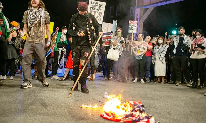 Pro-Palestine protesters burn an American flag in the street near the United Center where the Democratic National Convention is being held on August 22, 2024 in Chicago, Illinois. Tension between police and protesters is heightened due to violent protests in downtown Chicago earlier this week. (Photo by Jim Vondruska/Getty Images)