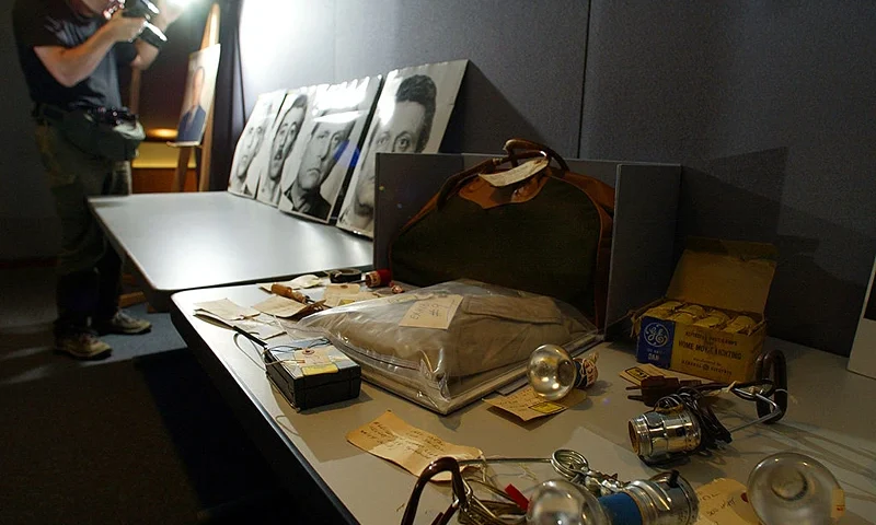 COLLEGE PARK, : A photographer takes a photo of evidence from the infamous Watergate break-in at the Democratic National Committee (DNC) headquarters at the Watergate Office Building in Washington, 17 June 1972. The US National Archives opened up and displayed some of the police evidence 13 June 2002 that has been sealed in archival warehouses for almost 30 years to mark the 30th anniversary of the historical crime. To the rear are arrest photo enlargements of the 4 Cubans from Miami, Valdez Martinez(L),Virgilio Gonzalez(L2), Bernard Barker, and Frank Sturgis(R) who committed the robbery and in the foreground are lights, film, a toolbag , a trenchcoat, and bugging equipment used in one of the most famous burglaries in political history. AFP Photo/Paul J. RICHARDS (Photo credit should read PAUL J. RICHARDS/AFP via Getty Images)