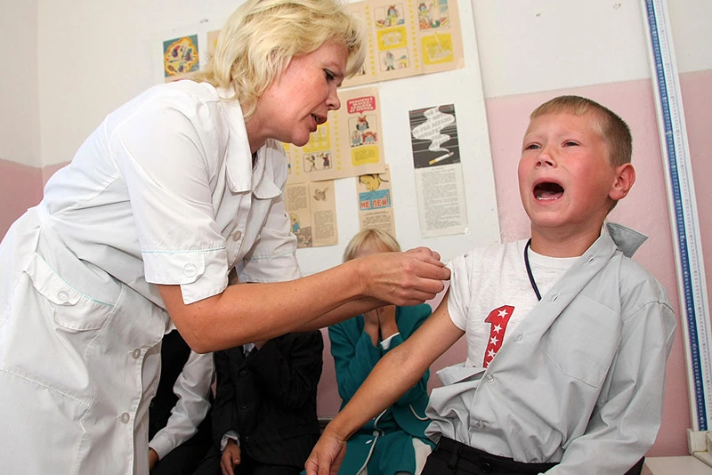 A Russian schoolboy cries as he gets a flu vaccination shot from the school nurse outside St. Petersburg in Podporozhye on September 2, 2009. The Russian academic year began nationwide on September 1.             AFP PHOTO / VIKTOR BARTENEV (Photo credit should read VIKTOR BARTENEV/AFP via Getty Images)