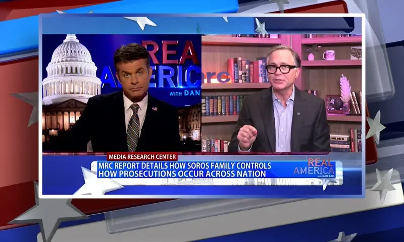 Video still from Real America on One America News Network showing a split screen of the host on the left side, and on the right side is the guest, Dan Schneider.