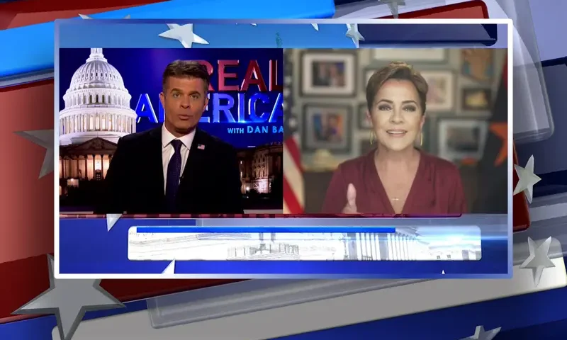 Video still from Real America on One America News Network showing a split screen of the host on the left side, and on the right side is the guest, Kari Lake.