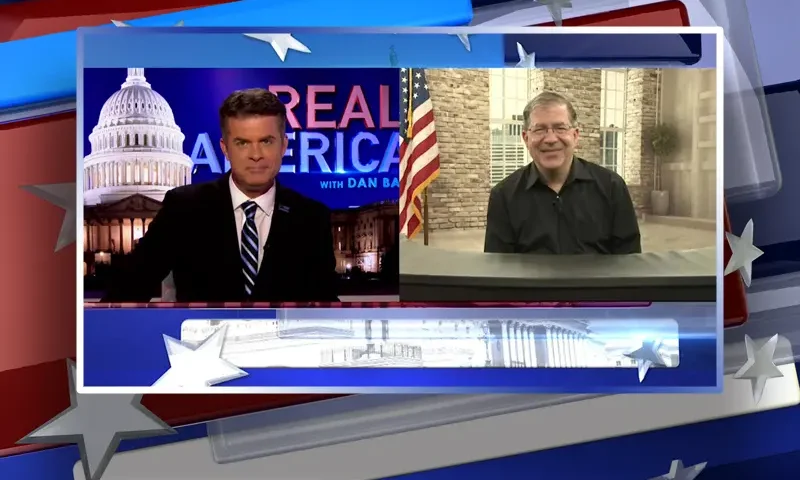 Video still from Real America on One America News Network showing a split screen of the host on the left side, and on the right side is the guest, Father Frank Pavone.