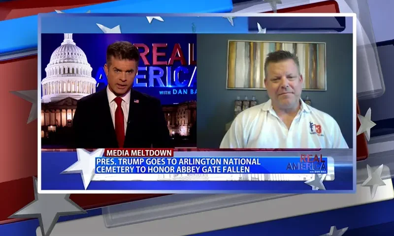 Video still from Real America on One America News Network showing a split screen of the host on the left side, and on the right side is the guest, Mark Schmitz.