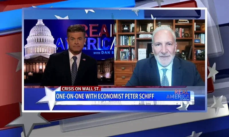 Video still from Real America on One America News Network showing a split screen of the host on the left side, and on the right side is the guest, Peter Schiff.