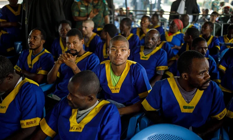 Marcel Malanga (C) sits among other accused of a failed coup attempt at the Ndolo Prison in Kinshasa on June 7, 2024. A trial opened in the Democratic Republic of Congo on Friday of around 50 people including several Americans over what the army said was a thwarted coup attempt last month. Armed men attacked the home of Economy Minister Vital Kamerhe in the early hours of May 19 before moving onto the nearby Palais de la Nation that houses President Felix Tshisekedi's offices. The army later announced on national TV that security forces had stopped "an attempted coup d'etat". (Photo by Arsene MPIANA / AFP) (Photo by ARSENE MPIANA/AFP via Getty Images)