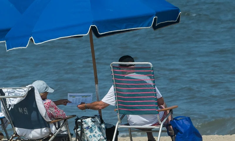 US President Joe Biden (R) shows a document to his wife First Lady Jill Biden while sitting at the beach in Cape Henlopen State Park, in Lewes, Delaware, on August 28, 2024. (Photo by ROBERTO SCHMIDT / AFP) (Photo by ROBERTO SCHMIDT/AFP via Getty Images)