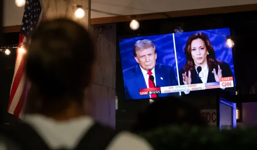 A walking past stops to watch a screen displaying the US Presidential debate between Vice President and Democratic presidential candidate Kamala Harris and former US President and Republican presidential candidate Donald Trump at The Admiral in Washington, DC, on September 10, 2024. (Photo by Allison Bailey / AFP) (Photo by ALLISON BAILEY/AFP via Getty Images)
