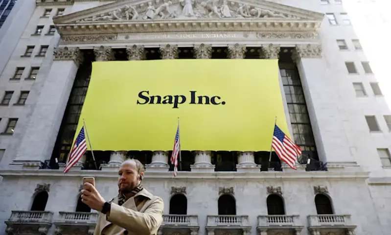 A man takes a photograph of the front of the New York Stock Exchange (NYSE) with a Snap Inc. logo hung on the front of it in New York, U.S., March 2, 2017. REUTERS/Lucas Jackson/File Photo