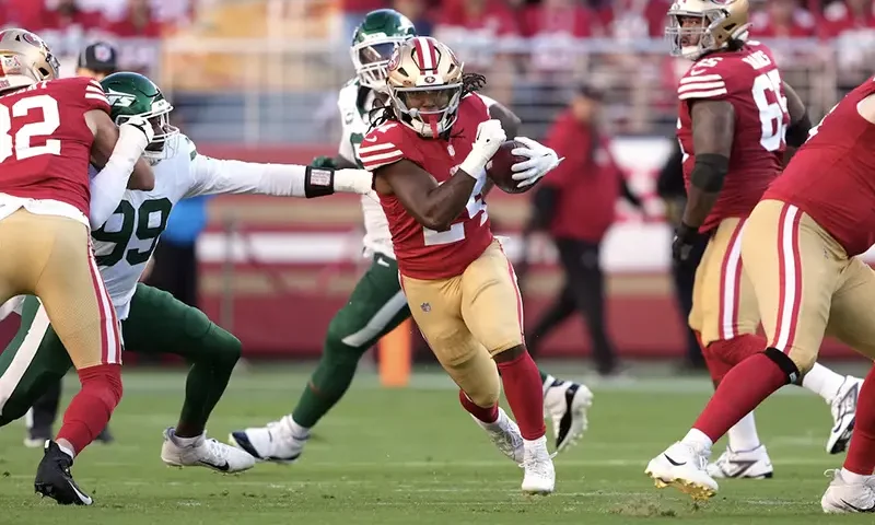 San Francisco 49ers running back Jordan Mason (center) carries the ball against New York Jets defensive end Will McDonald IV (99) during the first quarter at Levi's Stadium. Mandatory Credit: Darren Yamashita-Imagn Images